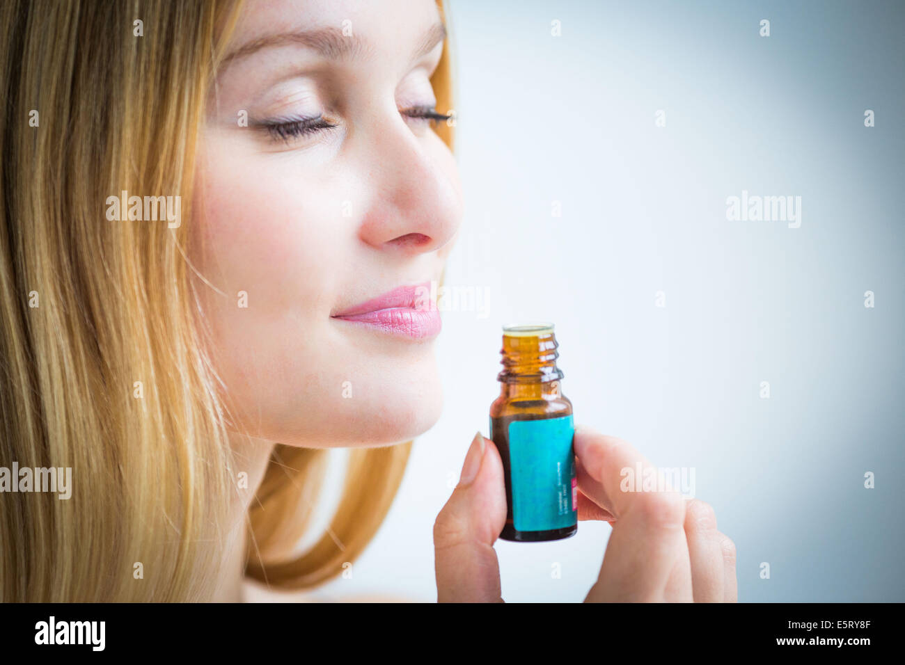 Donna annusare una bottiglia di olio essenziale. Foto Stock