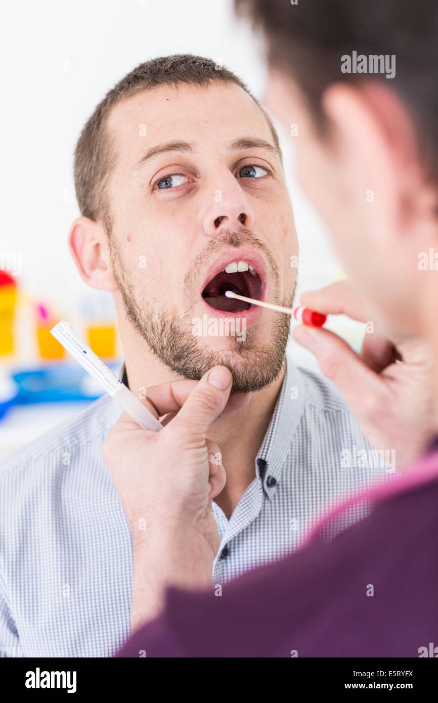 Medico usando un bastoncino di cotone per prelevare un campione da un paziente la gola del. Foto Stock