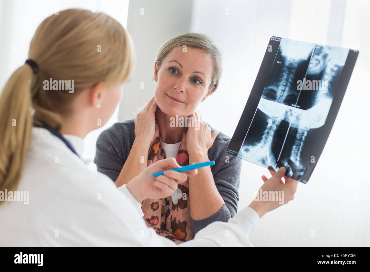 Medico guardando un della colonna vertebrale cervicale a raggi x del suo paziente. Foto Stock