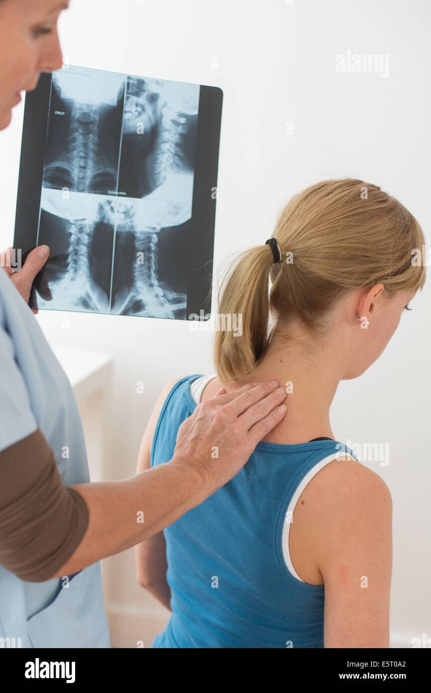 Medico guardando un della colonna vertebrale cervicale a raggi x del suo paziente. Foto Stock