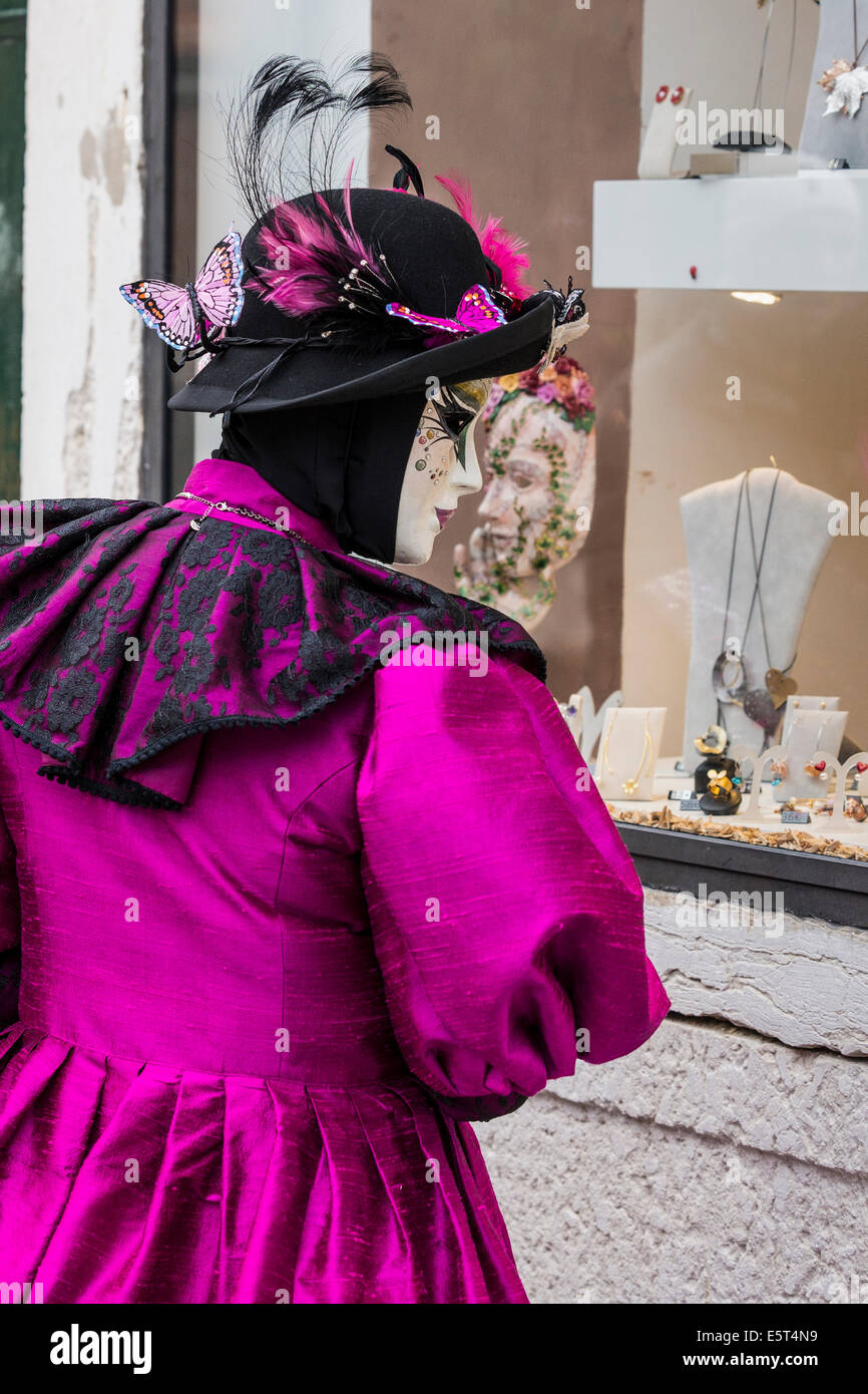 Signora in viola e costume nero appare in jewelery store window durante il carnevale di Venezia. Foto Stock