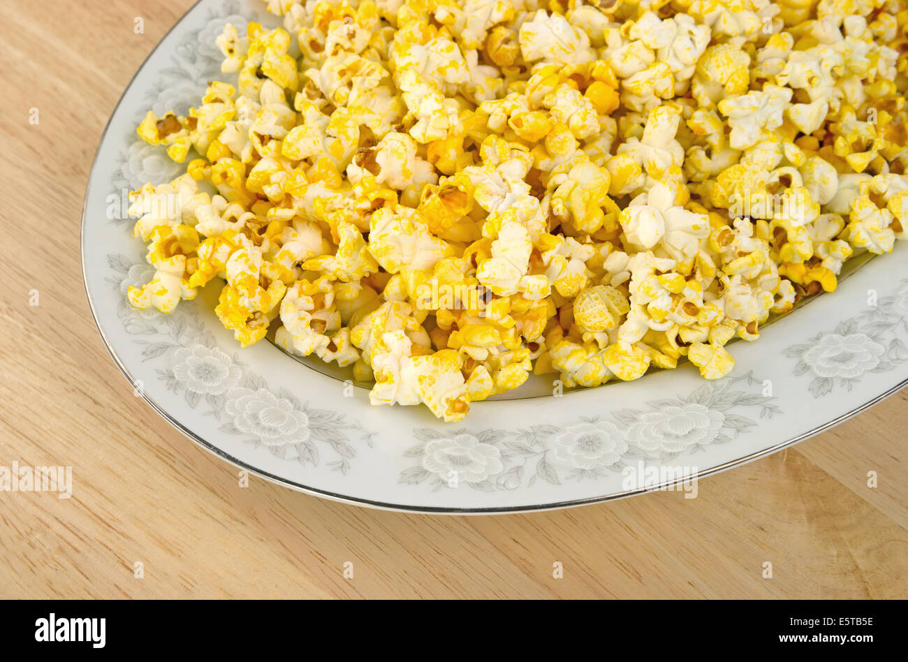 Chiudere la vista di un piatto riempito con popcorn su un tavolo da pranzo. Foto Stock