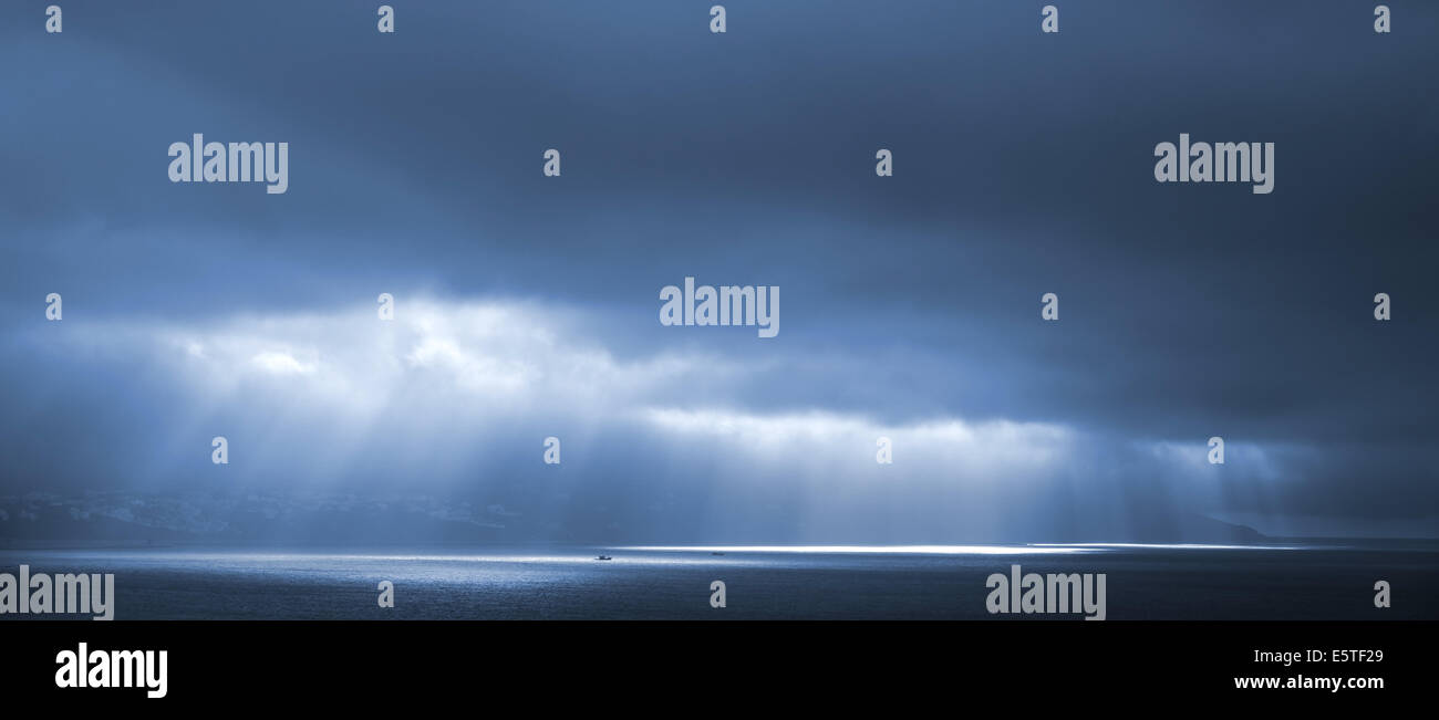 La luce del sole passa attraverso il blu nuvole temporalesche. Baia di Tangeri, Marocco Foto Stock
