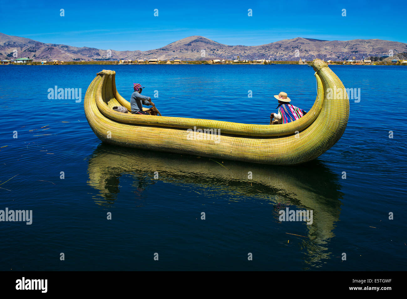 Due persone locali remare una barca tradizionale fatta di totora canne sul lago Titicaca, Perù meridionale, Perù Foto Stock