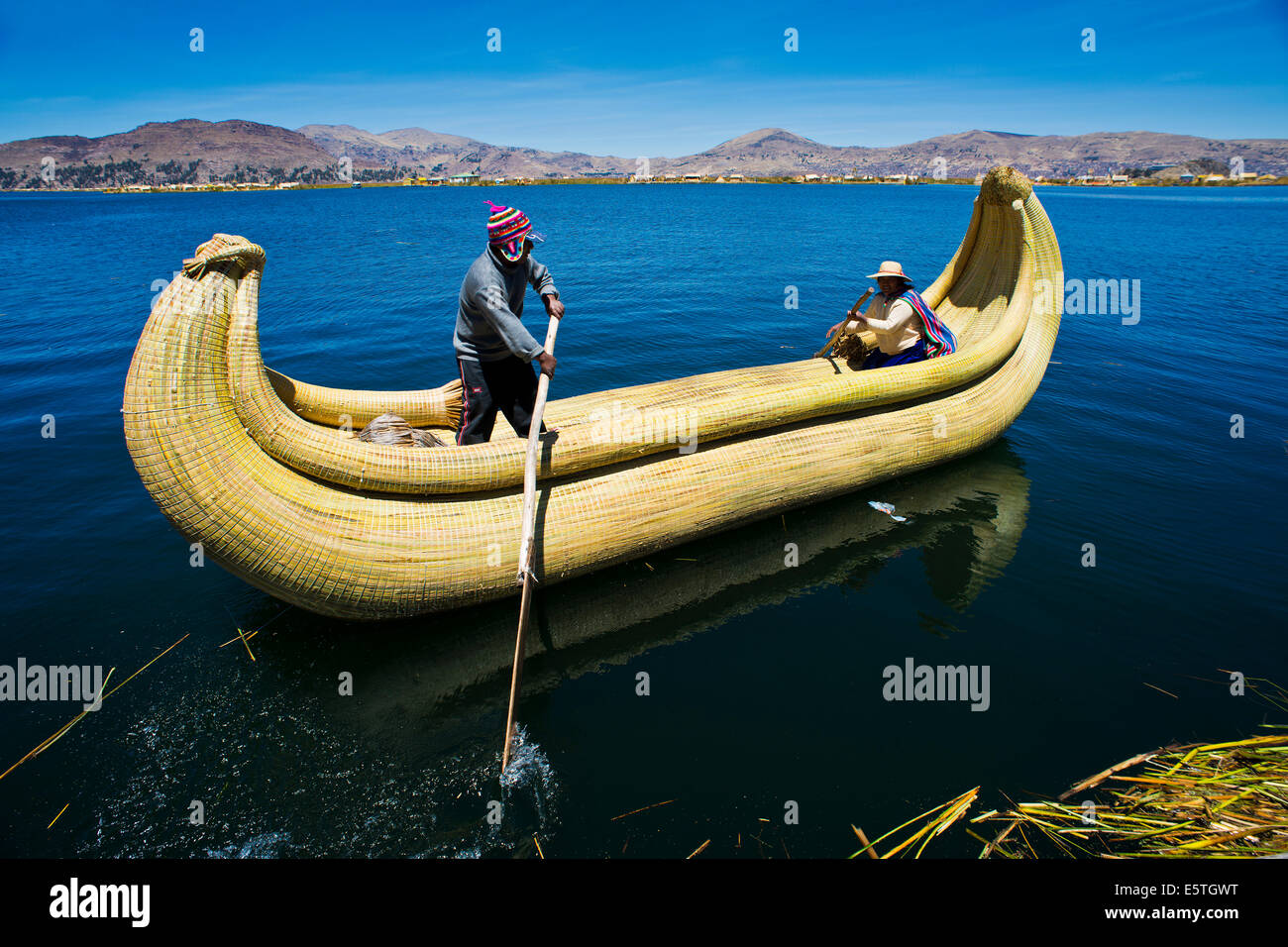 Due persone locali remare una barca tradizionale fatta di totora canne sul lago Titicaca, Perù meridionale, Perù Foto Stock