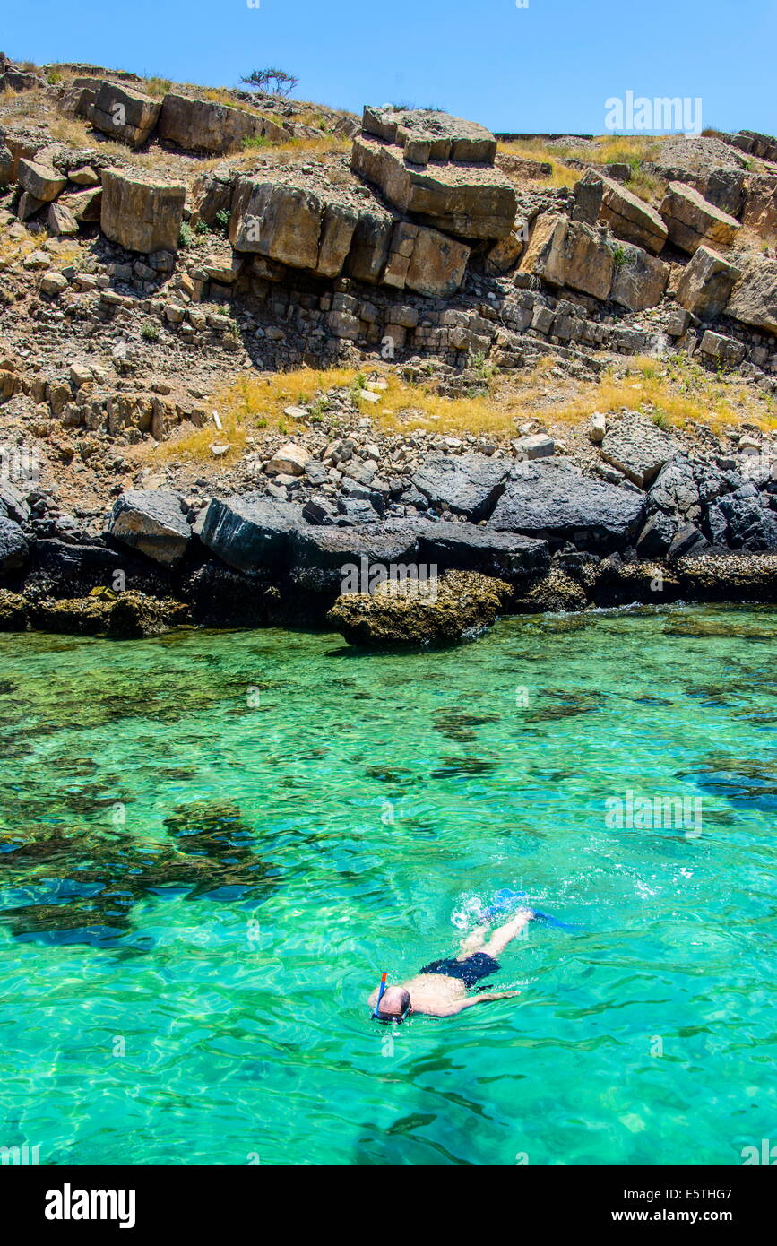 L uomo lo snorkelling nelle acque limpide del telegrafo isola in Khor ash-sham fiordo, Musandam, Oman, Medio Oriente Foto Stock