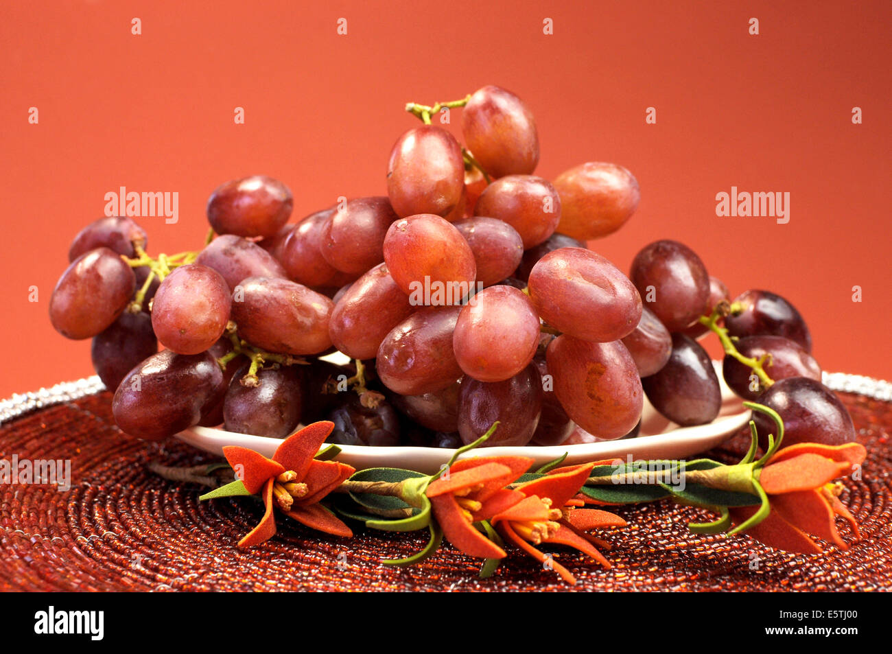 Piatto di frutta sani, uve rosse in rosso marrone autumn fall impostazione con fiori. Foto Stock