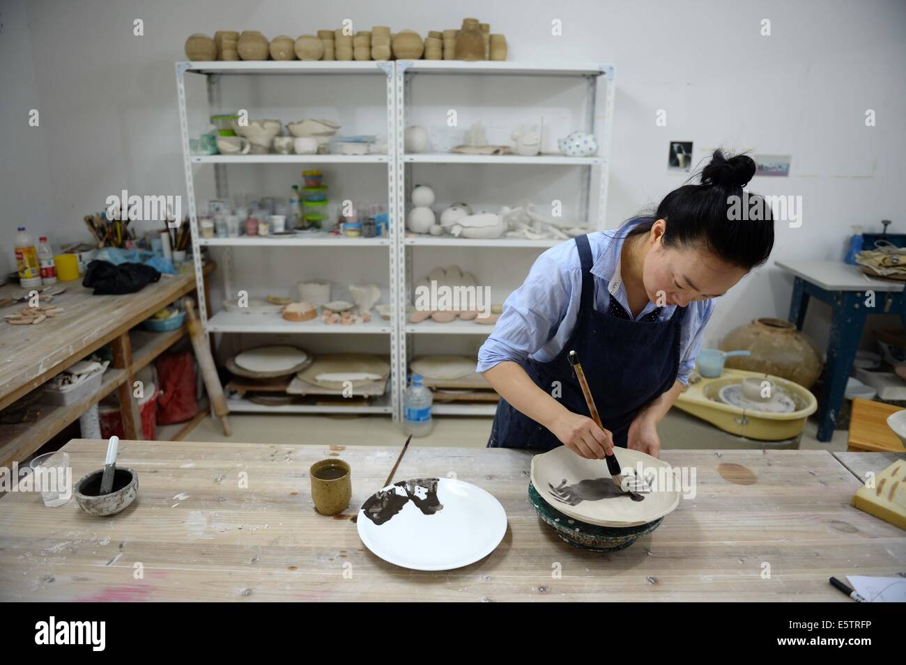 (140806) -- Pechino, il 6 agosto 2014 (Xinhua) -- Zhang Lingyun lavora in uno studio nella sua casa di Jingdezhen, Cina orientale della provincia di Jiangxi, luglio 18, 2014. Zhang Lingyun è 40. È stato 20 anni dell'artista in ceramica è venuto a Jingdezhen, della Cina di porcellana "capitale". Zhang della storia con la ceramica ha avuto un casuale, romantico inizio: Lei sapeva a malapena a nulla sulla ceramica prima ha incontrato il nome 'Ceramica Jingdezhen Institute (JCI)' quando si applica per il college. "Ceramiche sembrava interessante così ho depositato la domanda di JCI.' Il Capriccio di impulso ha fatto una grande differenza in Zhang la vita. Egli Foto Stock