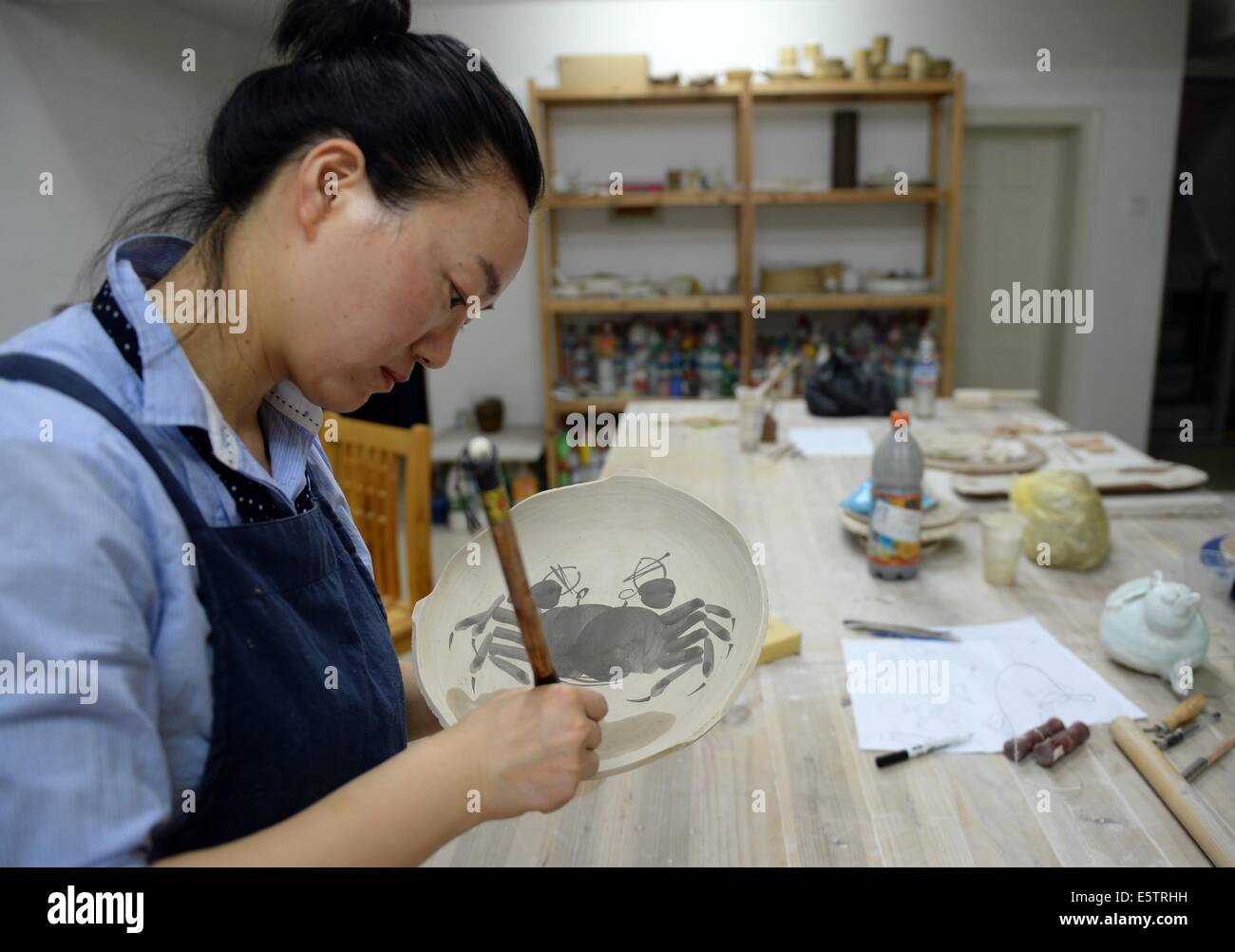 (140806) -- Pechino, il 6 agosto 2014 (Xinhua) -- Zhang Lingyun lavora in uno studio nella sua casa di Jingdezhen, Cina orientale della provincia di Jiangxi, luglio 18, 2014. Zhang Lingyun è 40. È stato 20 anni dell'artista in ceramica è venuto a Jingdezhen, della Cina di porcellana "capitale". Zhang della storia con la ceramica ha avuto un casuale, romantico inizio: Lei sapeva a malapena a nulla sulla ceramica prima ha incontrato il nome 'Ceramica Jingdezhen Institute (JCI)' quando si applica per il college. "Ceramiche sembrava interessante così ho depositato la domanda di JCI.' Il Capriccio di impulso ha fatto una grande differenza in Zhang la vita. Egli Foto Stock
