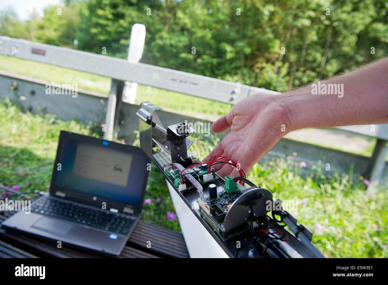 Alexander Schmidt, co-sviluppatore del prototipo della misurazione del rumore facility con dispositivi di conteggio di marker posti trattiene il dispositivo che passa in un marcatore post accanto a un computer portatile vicino Loewenstein, Germania, 06 agosto 2014. Questo serve a misurare la velocità e il livello di suoni. I dati possono essere letti su un laptop. Foto: Inga Kjer/dpa Foto Stock