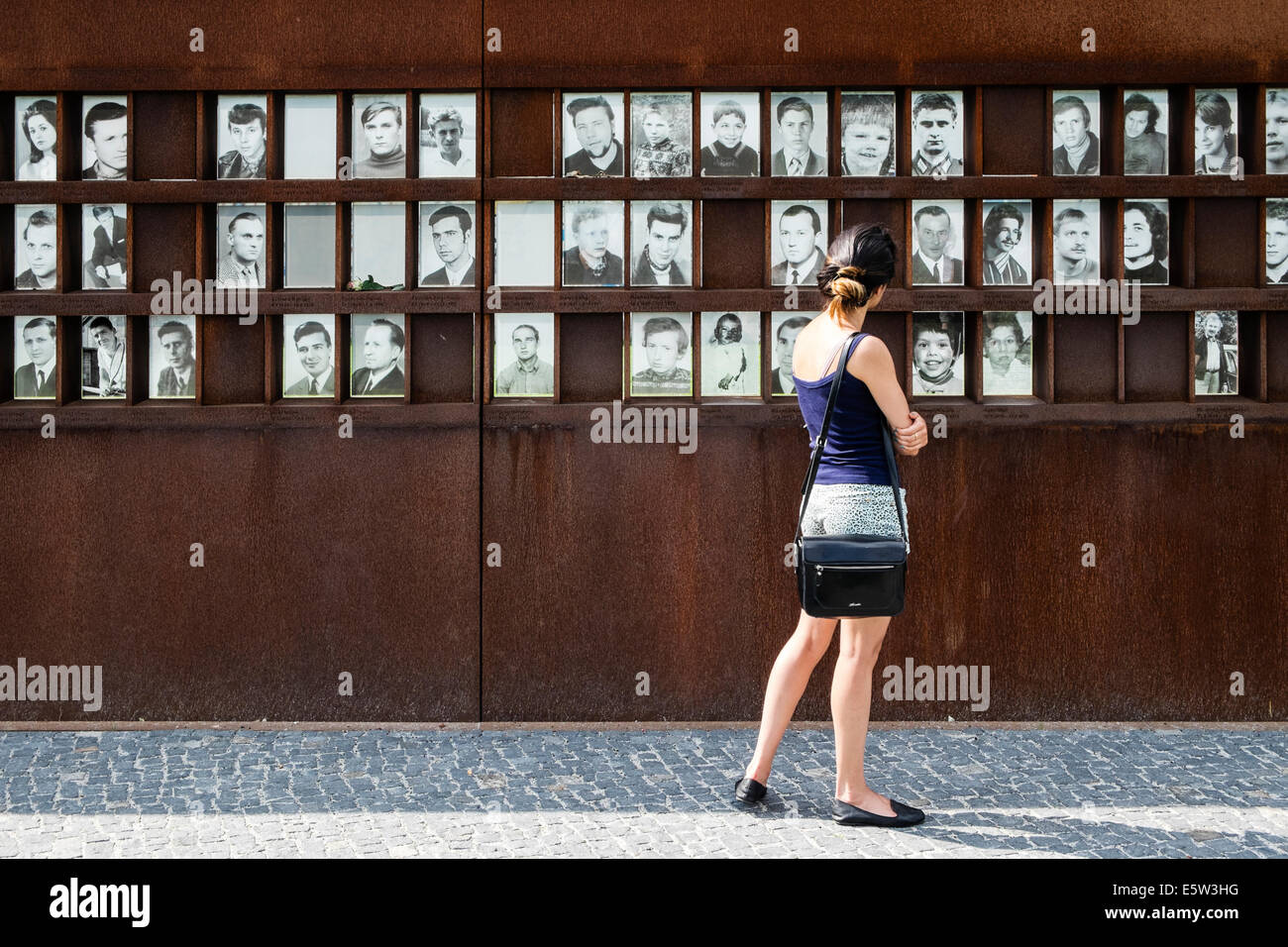 Donna che guarda le foto di vittime di tentativi di fuga attraverso il muro di Berlino, Bernauer Strasse Memorial Park a Berlino Germania Foto Stock