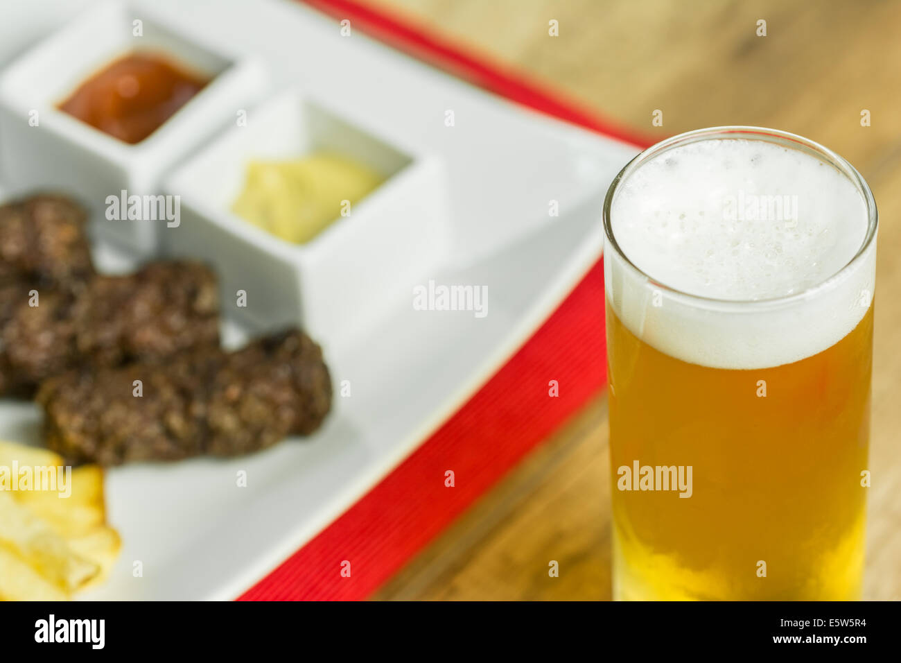 Tradizionale rumena Mici e patate fritte con ketchup, senape e bicchiere di birra Foto Stock