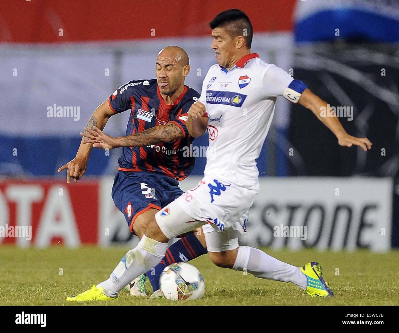 Asuncion in Paraguay. Il 6 agosto, 2014. Nacional di Jose Caceres (R) il sistema VIES per la palla con Juan Mercier (L) di San Lorenzo, durante il loro primo-leg partita finale del 2014 Coppa Libertadores, tenutasi al Defensores del Chaco Stadium, in Asuncion in Paraguay, su il 6 agosto 2014. Credito: José Romero/TELAM/Xinhua/Alamy Live News Foto Stock