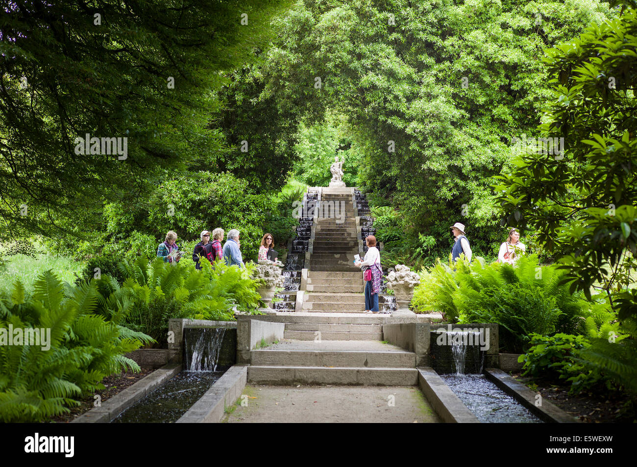 Guida con i visitatori di un verdeggiante giardino paesaggistico con acqua ruscelli a Holker Hall in Cumbria Regno Unito Foto Stock