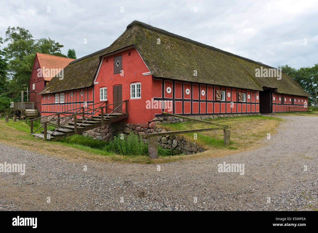 Con il tetto di paglia, dipinta di rosso semi-edificio con travi di legno con il vecchio mulino, Viking Centre Fyrkat, Fyrkat, Hobro, Danimarca Foto Stock