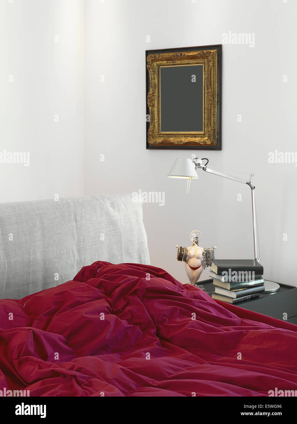 Dettaglio del letto con coperta di rosso in una moderna camera da letto con lampada da tavolo Foto Stock