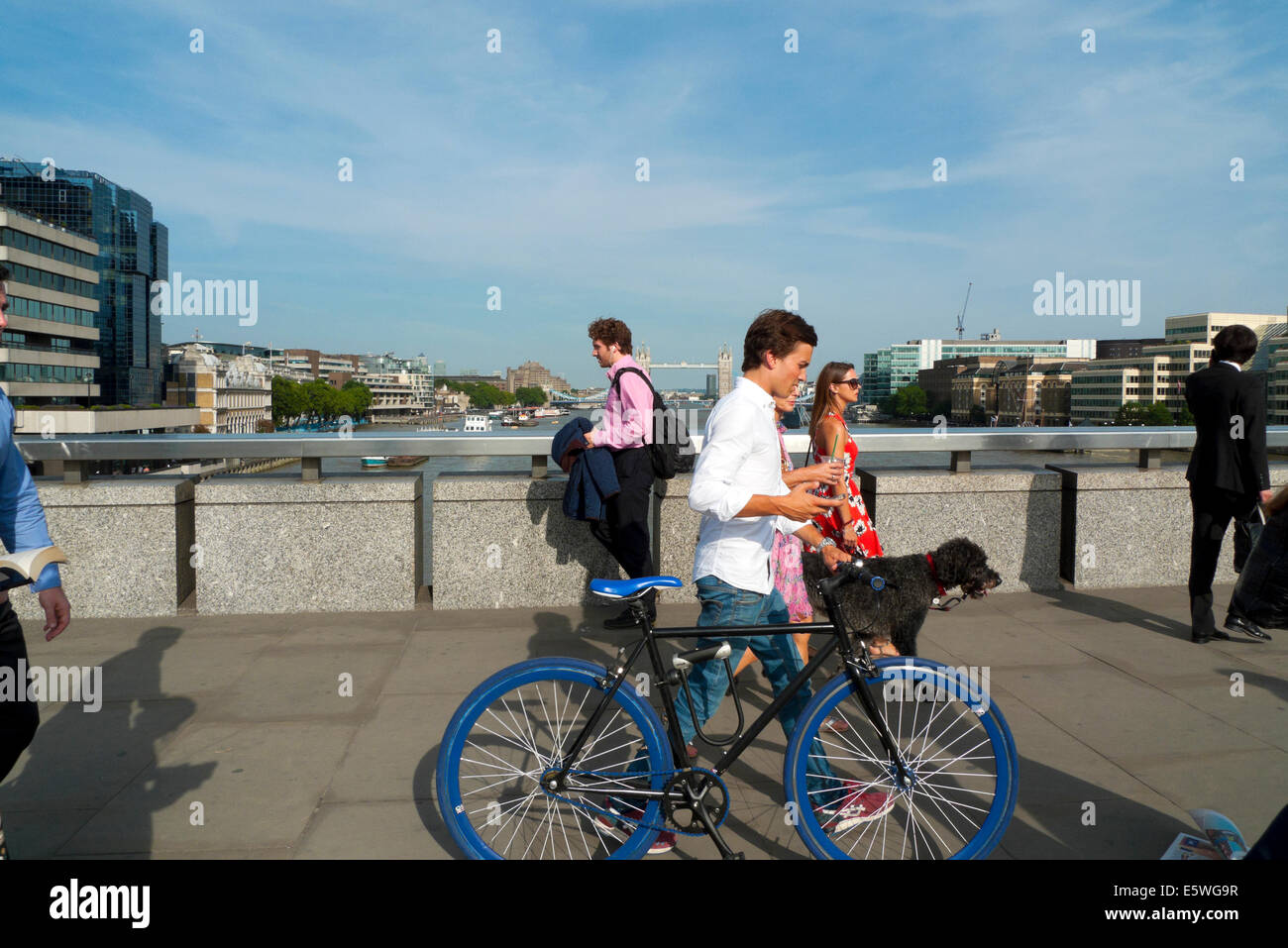 L'uomo attraversando il Ponte di Londra in estate il sole a piedi spingendo una bicicletta blu Londra UK KATHY DEWITT Foto Stock