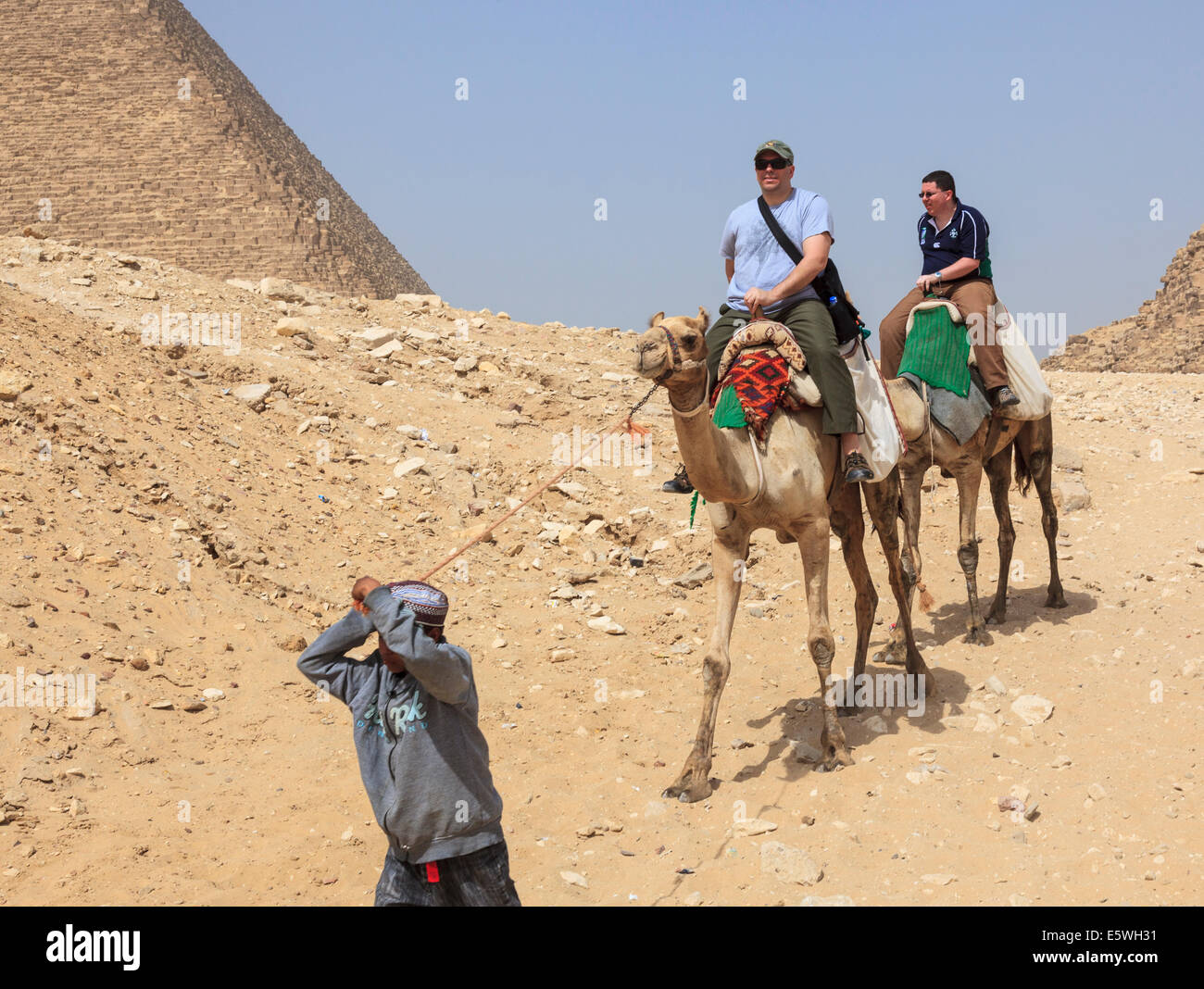 I turisti a cavallo di cammelli da la Grande Piramide di Giza in Egitto Foto Stock