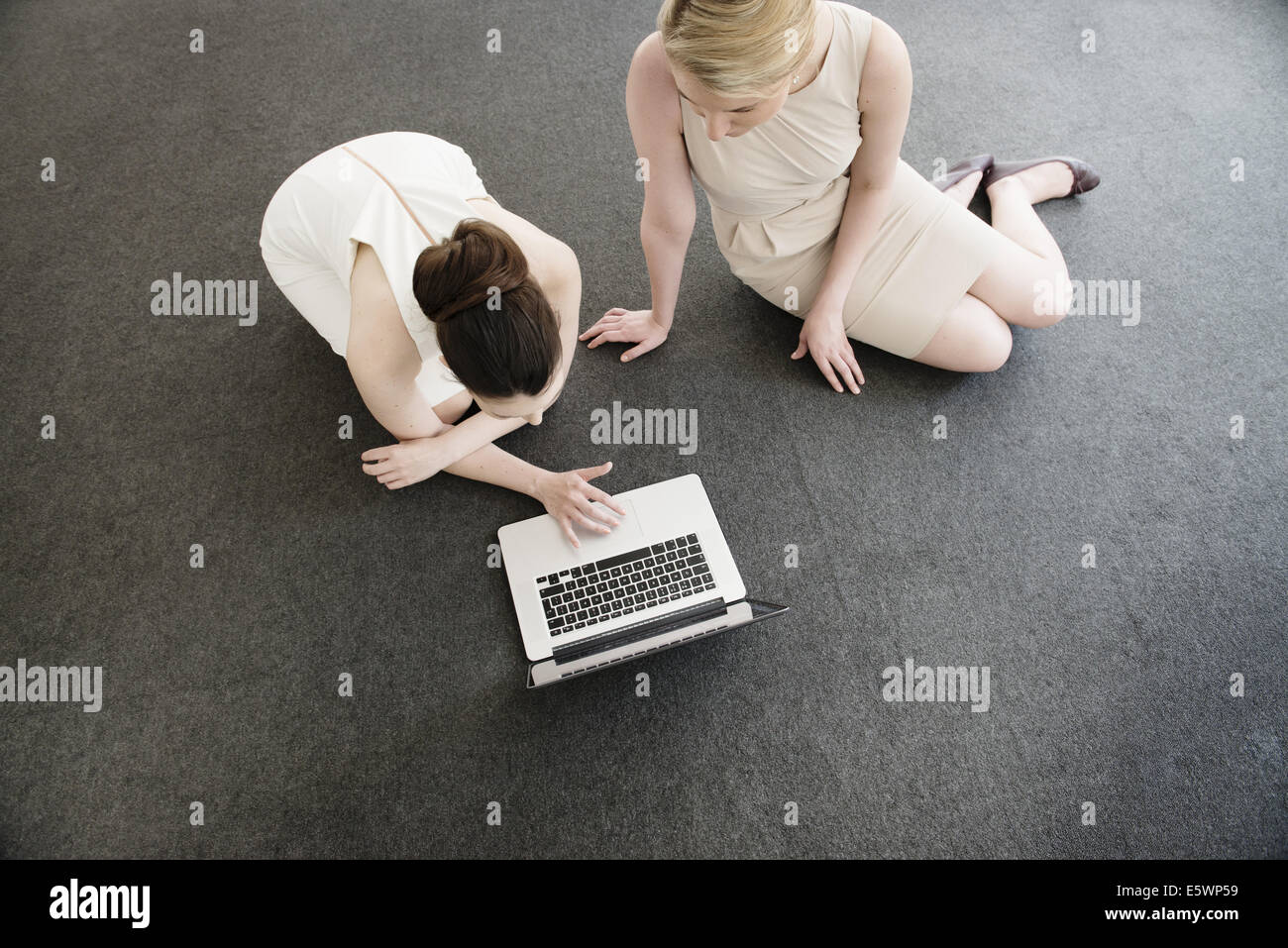 Vista aerea di due giovani imprenditrici utilizzando laptop sul pavimento nel nuovo ufficio Foto Stock