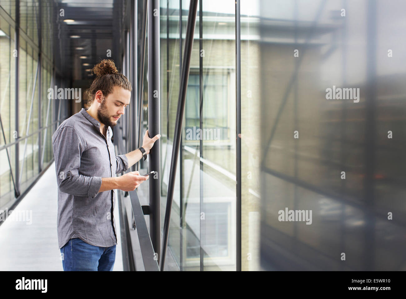 L'uomo utilizza lo smartphone in corridoio Foto Stock