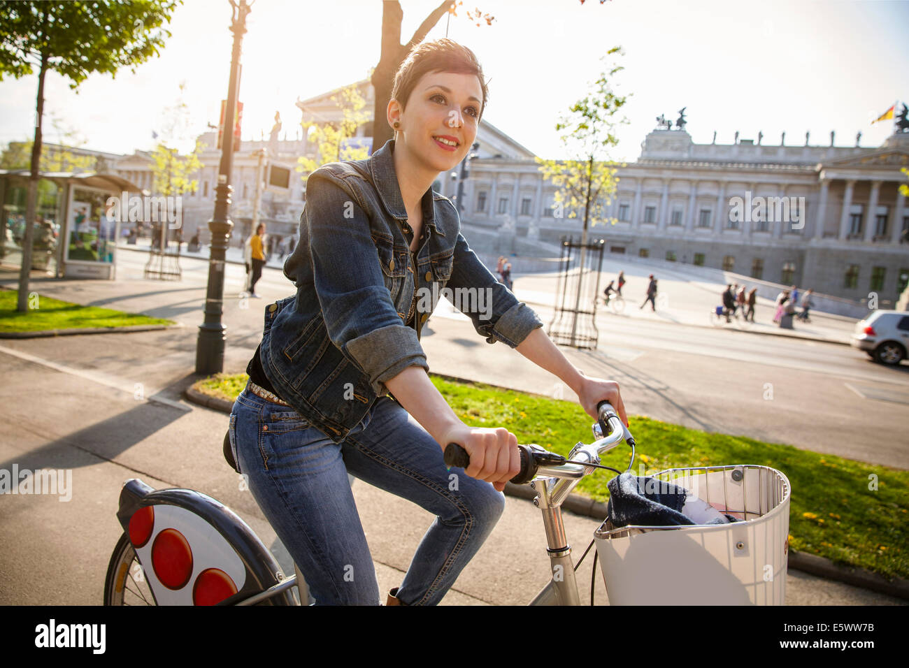 Giovane donna adulta in bicicletta attraverso la città, Vienna, Austria Foto Stock