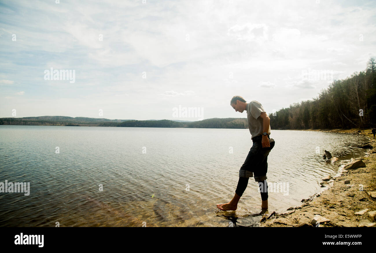Giovane maschio escursionista tenendo apprensivi pagaia in lago Foto Stock
