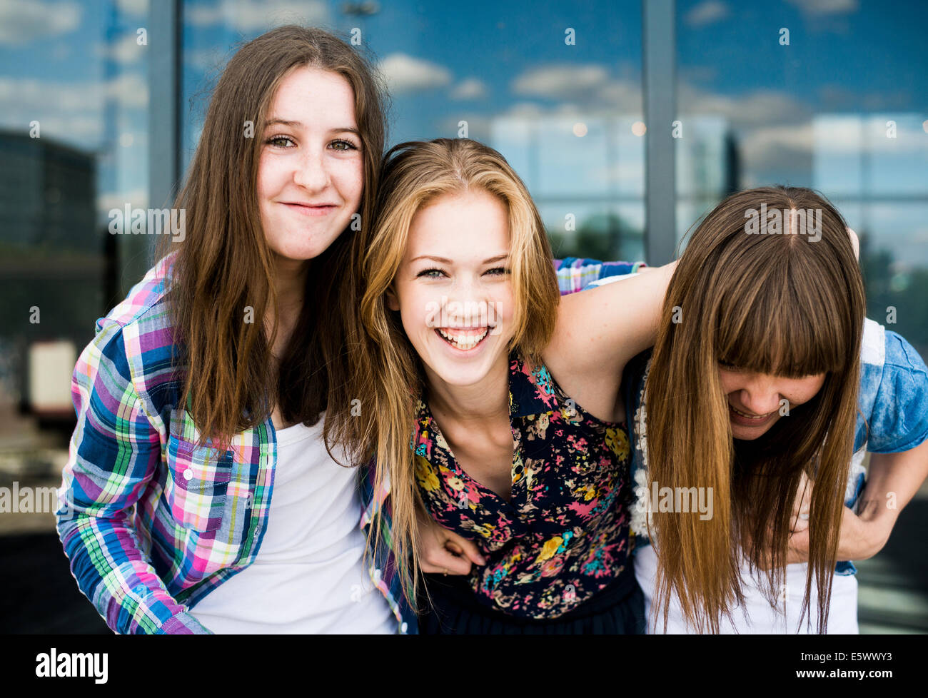 Ritratto di tre giovani donne ridere nella parte anteriore di vetro edificio per uffici Foto Stock