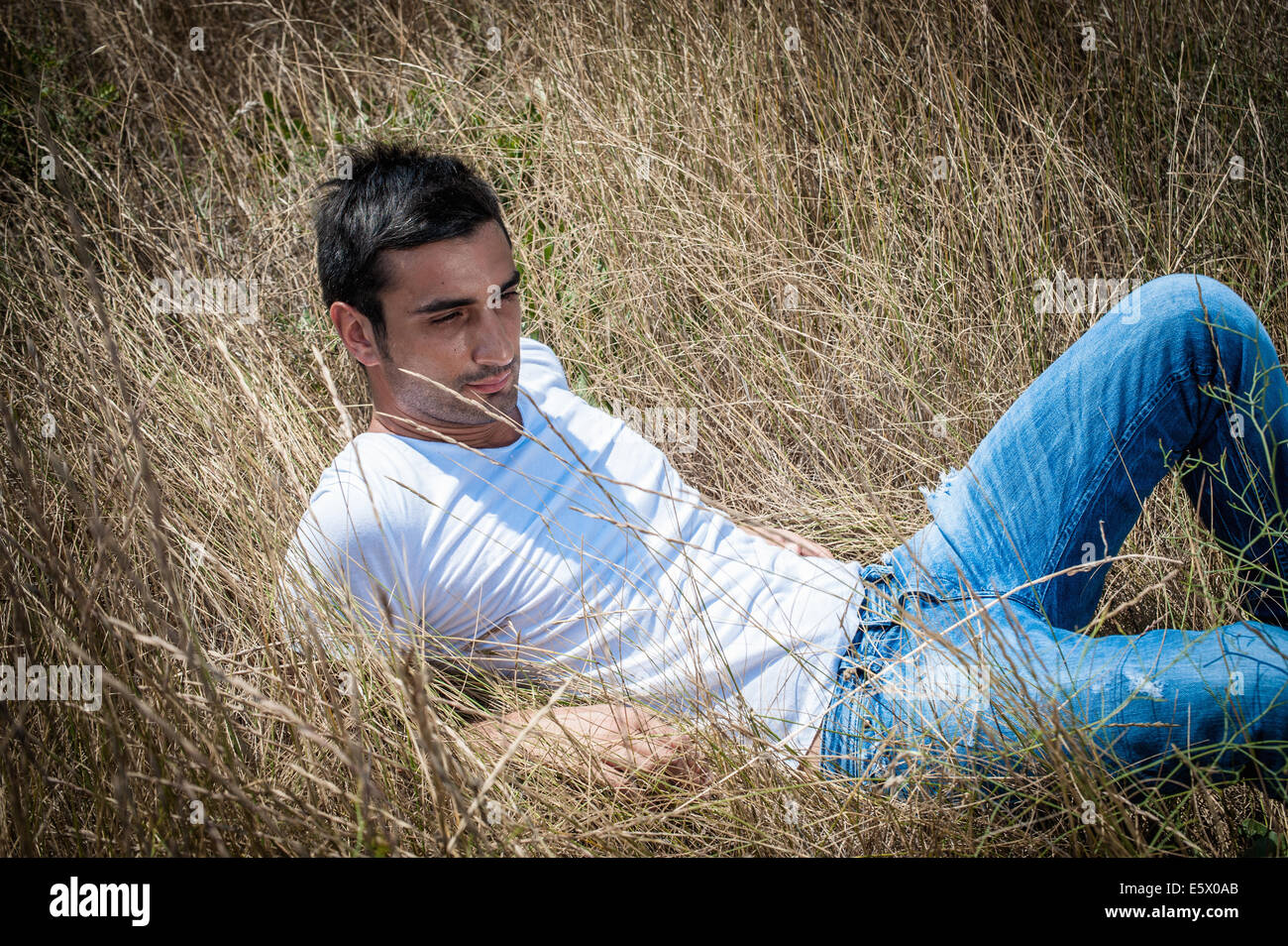Ritratto di giovane uomo reclinate in erba lunga Foto Stock