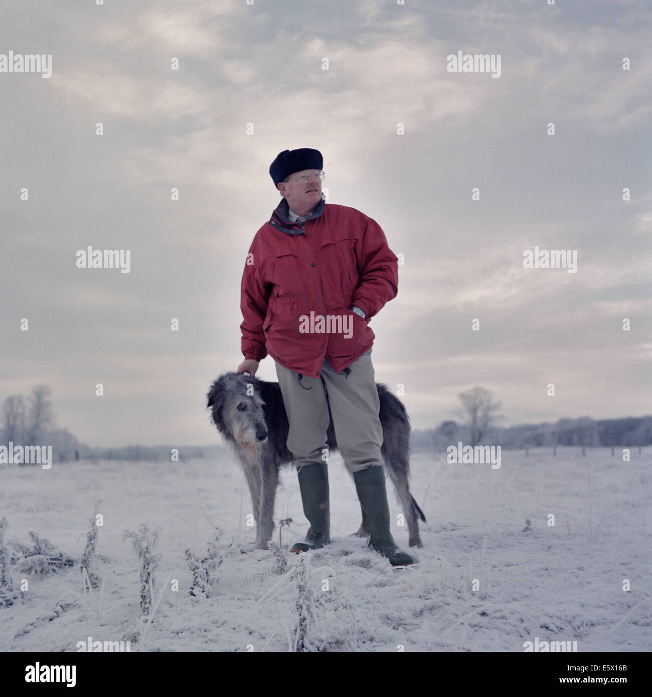 Ritratto di uomo con deerhound in coperta di neve campo Foto Stock