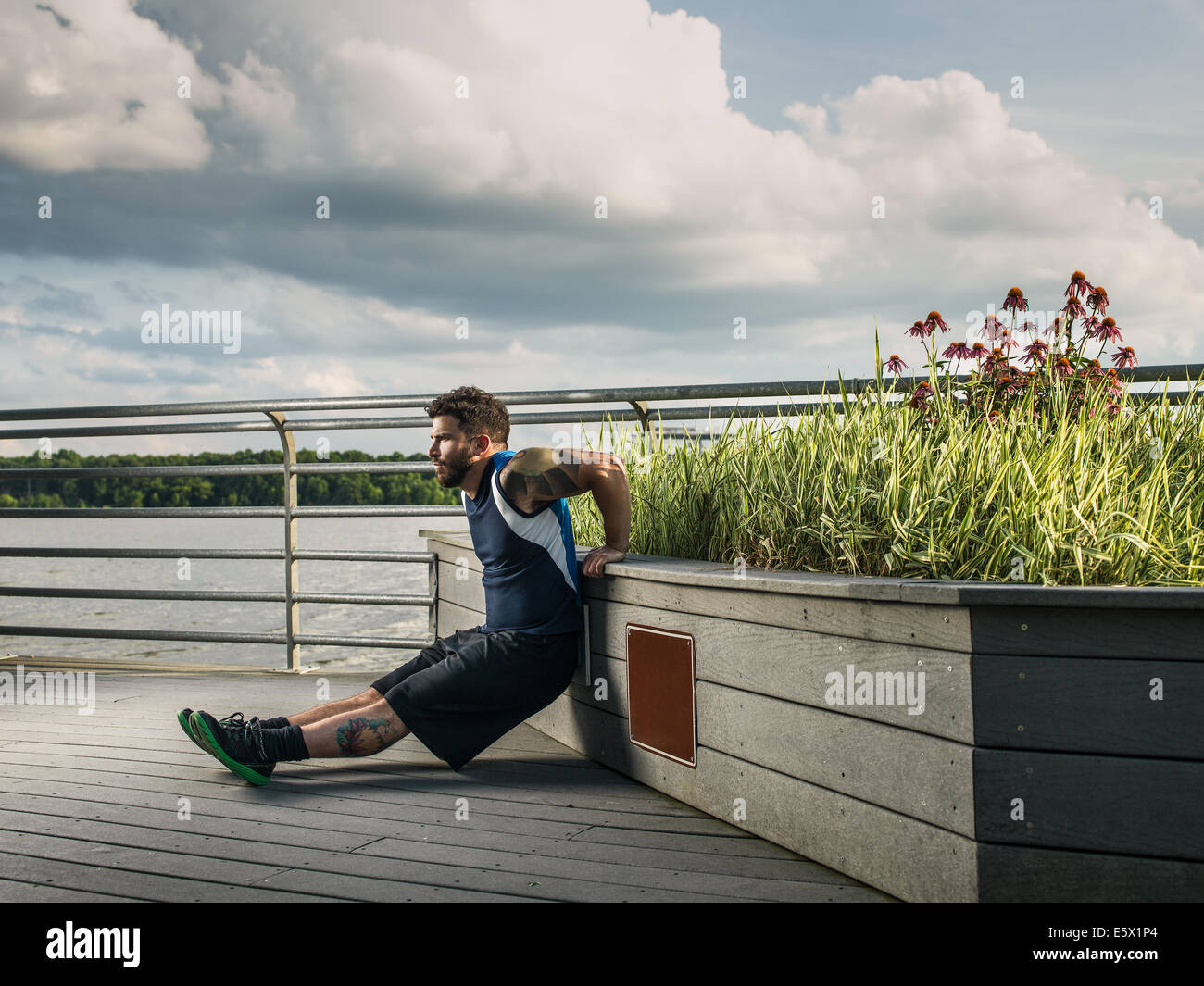 Giovane uomo facendo ups di spinta contro il lago di pier sede Foto Stock