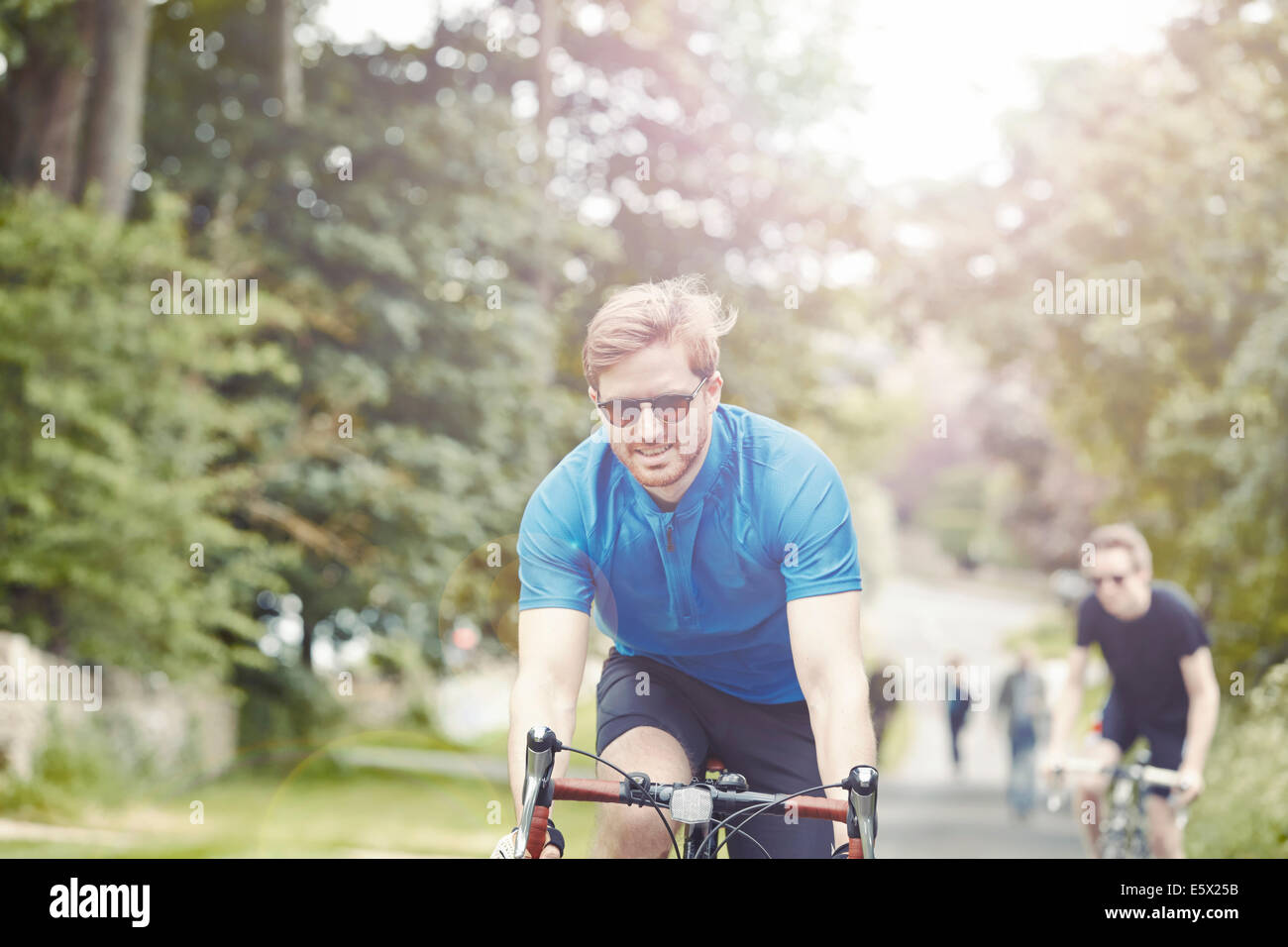 I ciclisti equitazione sulla frondosa strada di campagna, Cotswolds, REGNO UNITO Foto Stock