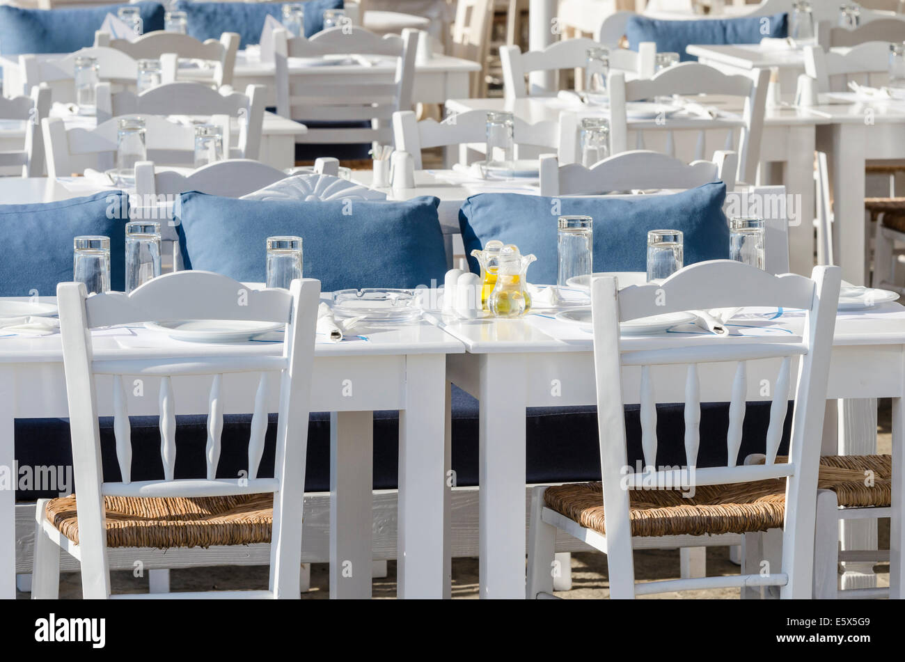 Set di tabelle per la cena in una taverna sul lungomare a Naoussa Town, isola di Paros, Cicladi Grecia Foto Stock