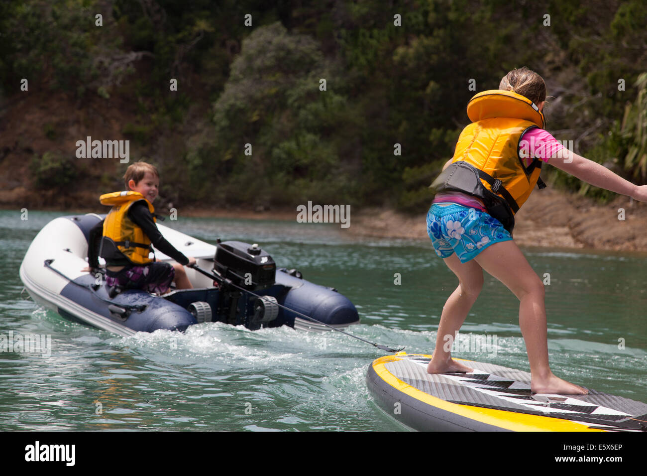 Fratello nel motore di traino dinghy sorella permanente sulla paddleboard Foto Stock