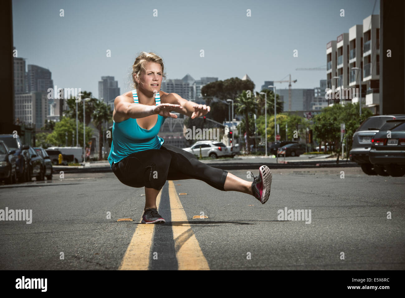 Giovane donna adulta in equilibrio su un piede in strada Foto Stock