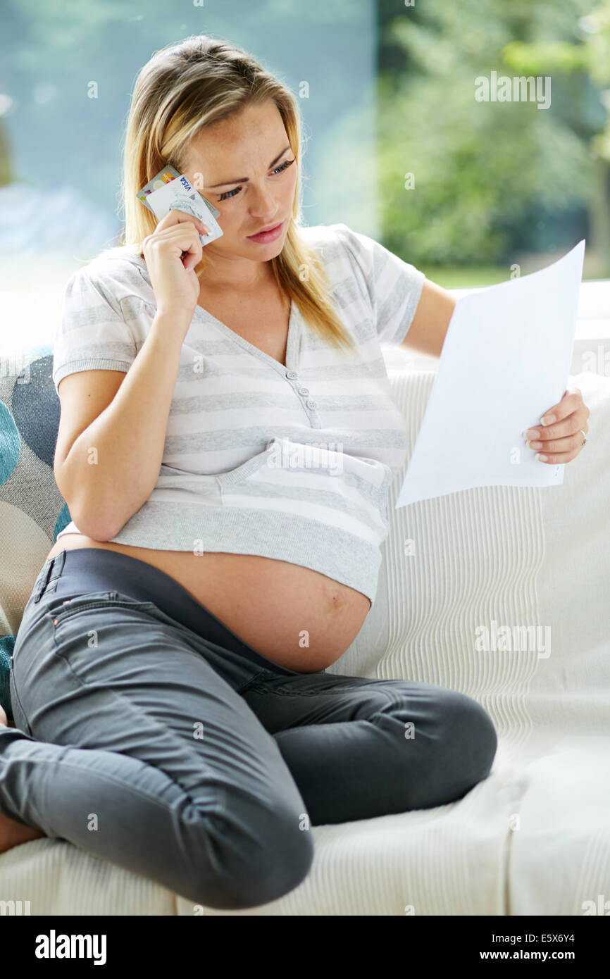 Donna incinta guardando estratto conto della carta di credito Foto Stock