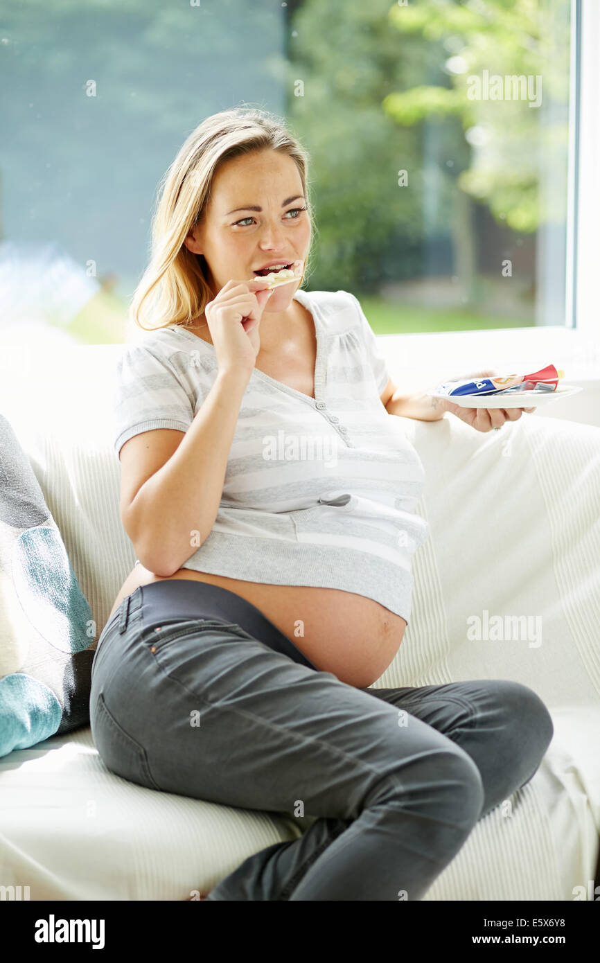 Donna incinta mangiando snack Foto Stock