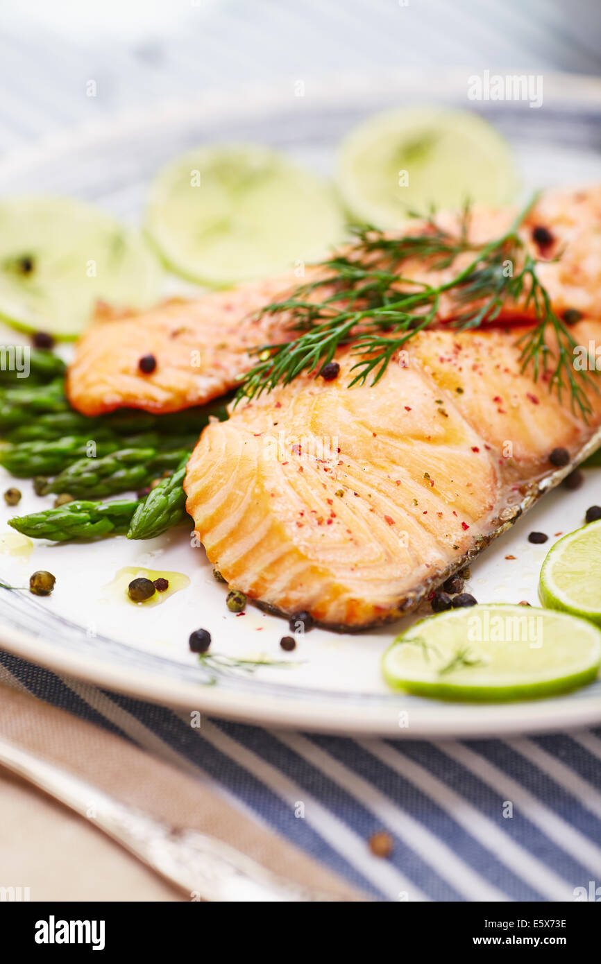 Filetto di salmone con asparagi in un piatto con un bordo blu e una striscia di colore blu placemat Foto Stock