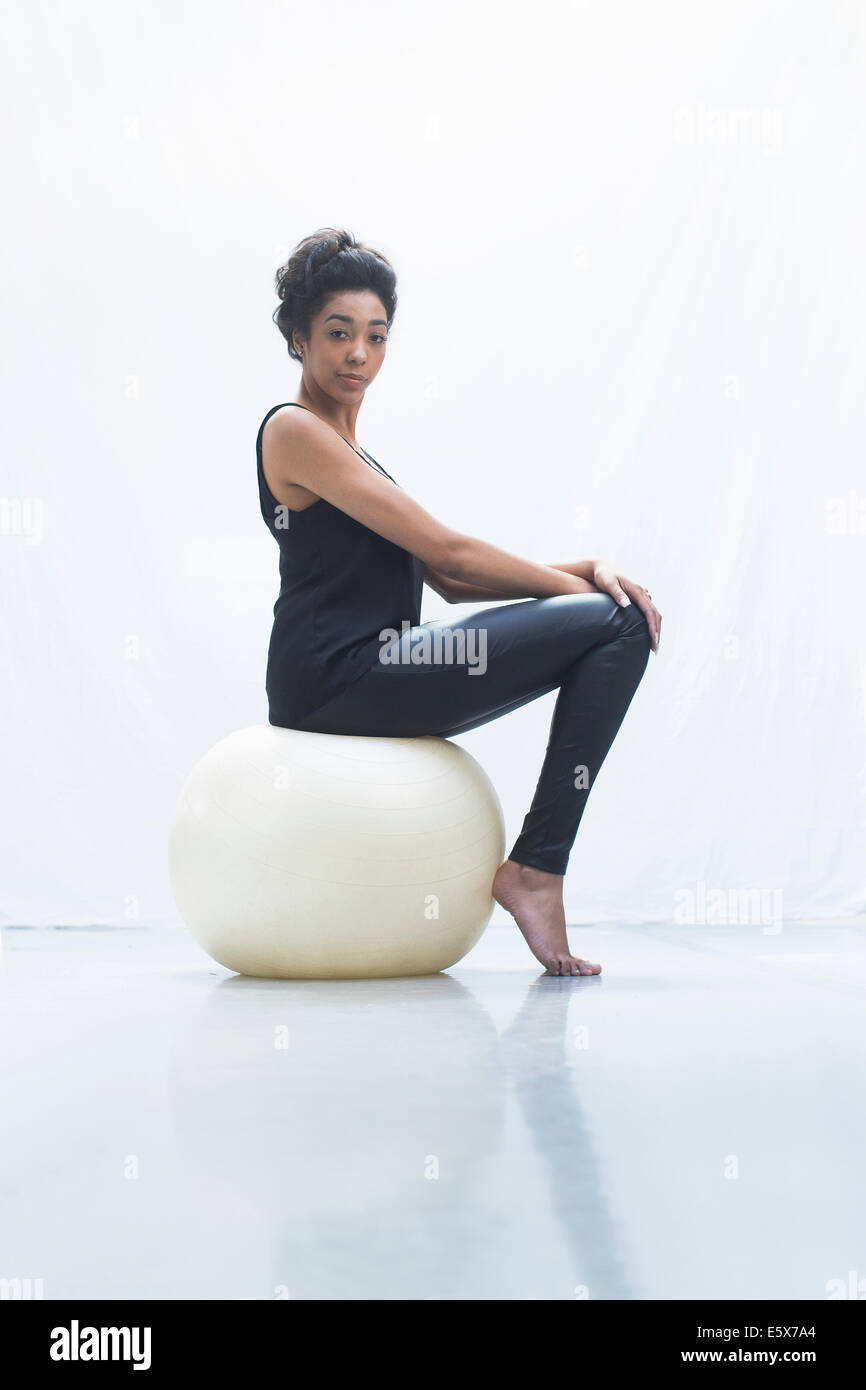 Giovane donna seduta sulla sfera di fitness Foto Stock