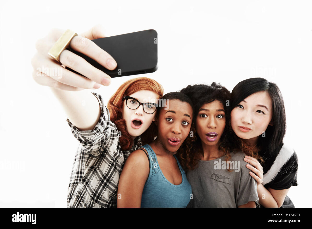 Ritratto in studio di quattro giovani donne che assumono selfie sullo smartphone Foto Stock