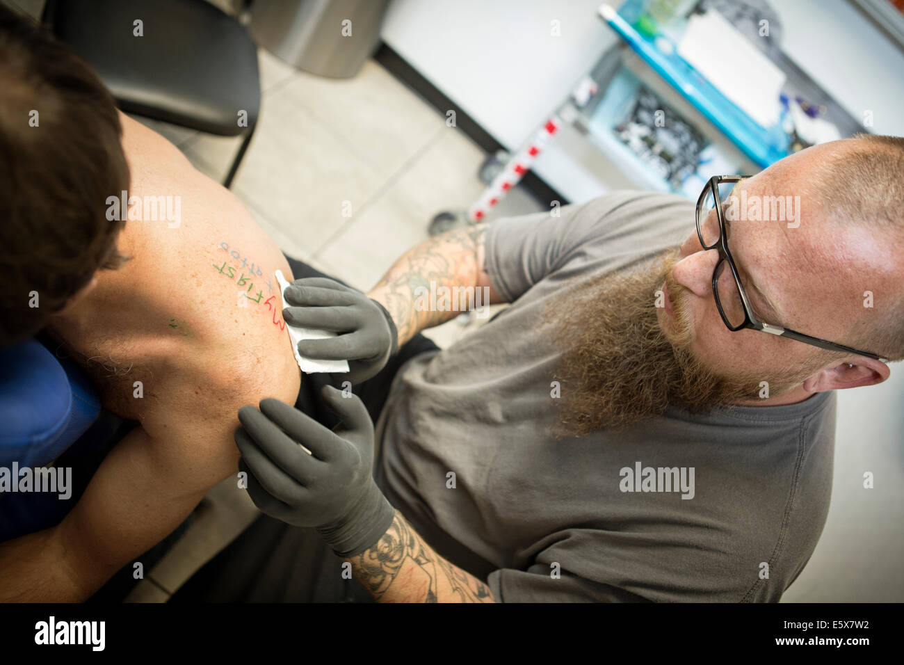 Tattoo Artist finendo un tatuaggio fresco Foto Stock