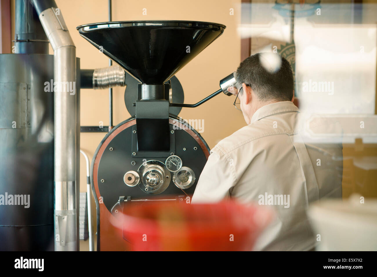 Vista posteriore di uomo maturo con la tostatura del caffè macchina del caffè Foto Stock
