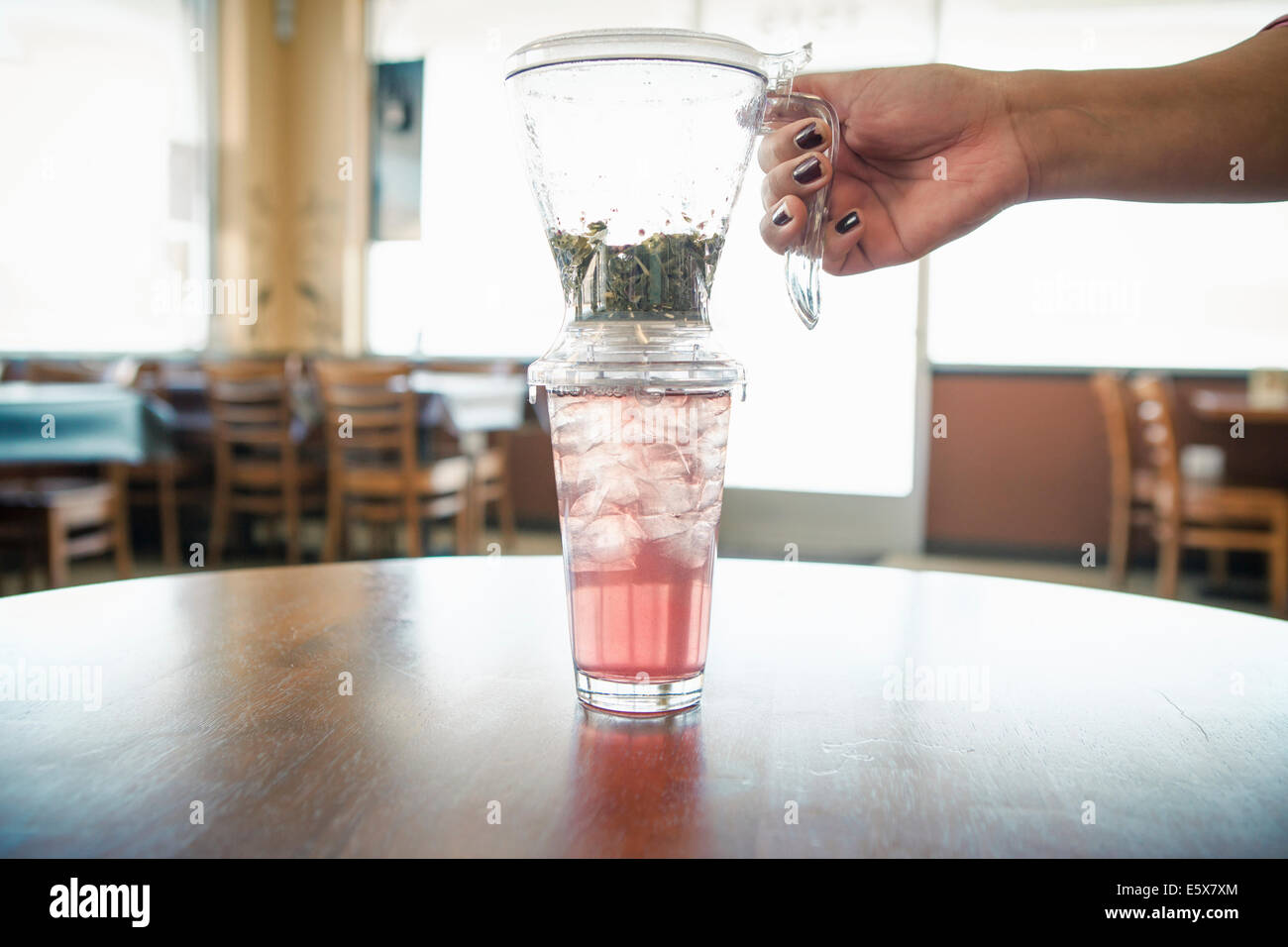 Mano femmina con iced tè alle erbe e il filtro in cafe Foto Stock