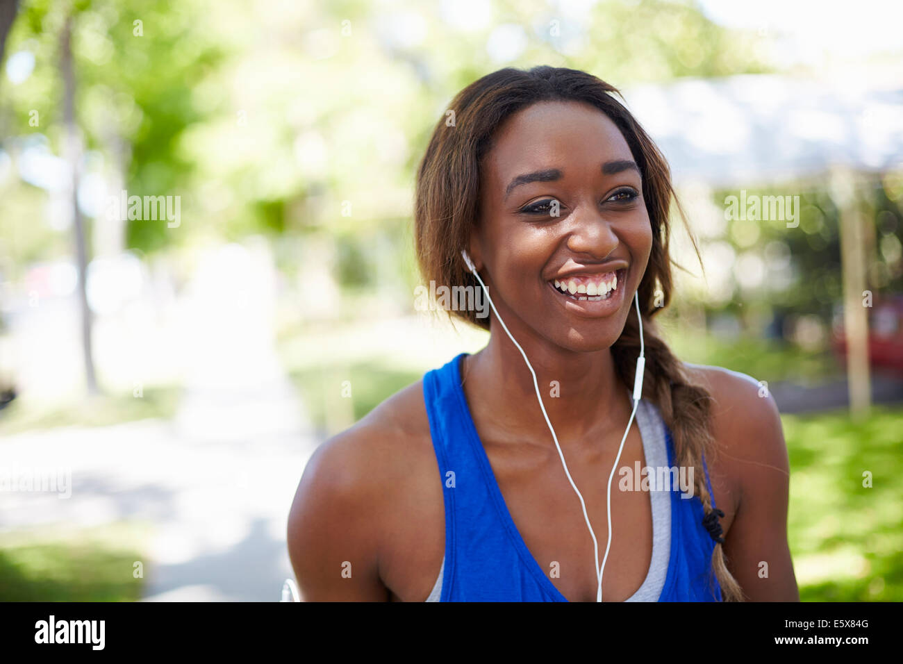 Giovani femmine runner indossa gli auricolari in posizione di parcheggio Foto Stock
