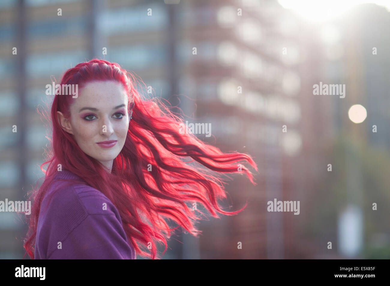 Ritratto di giovane donna con lunghi capelli rosa sul tetto della città Foto Stock