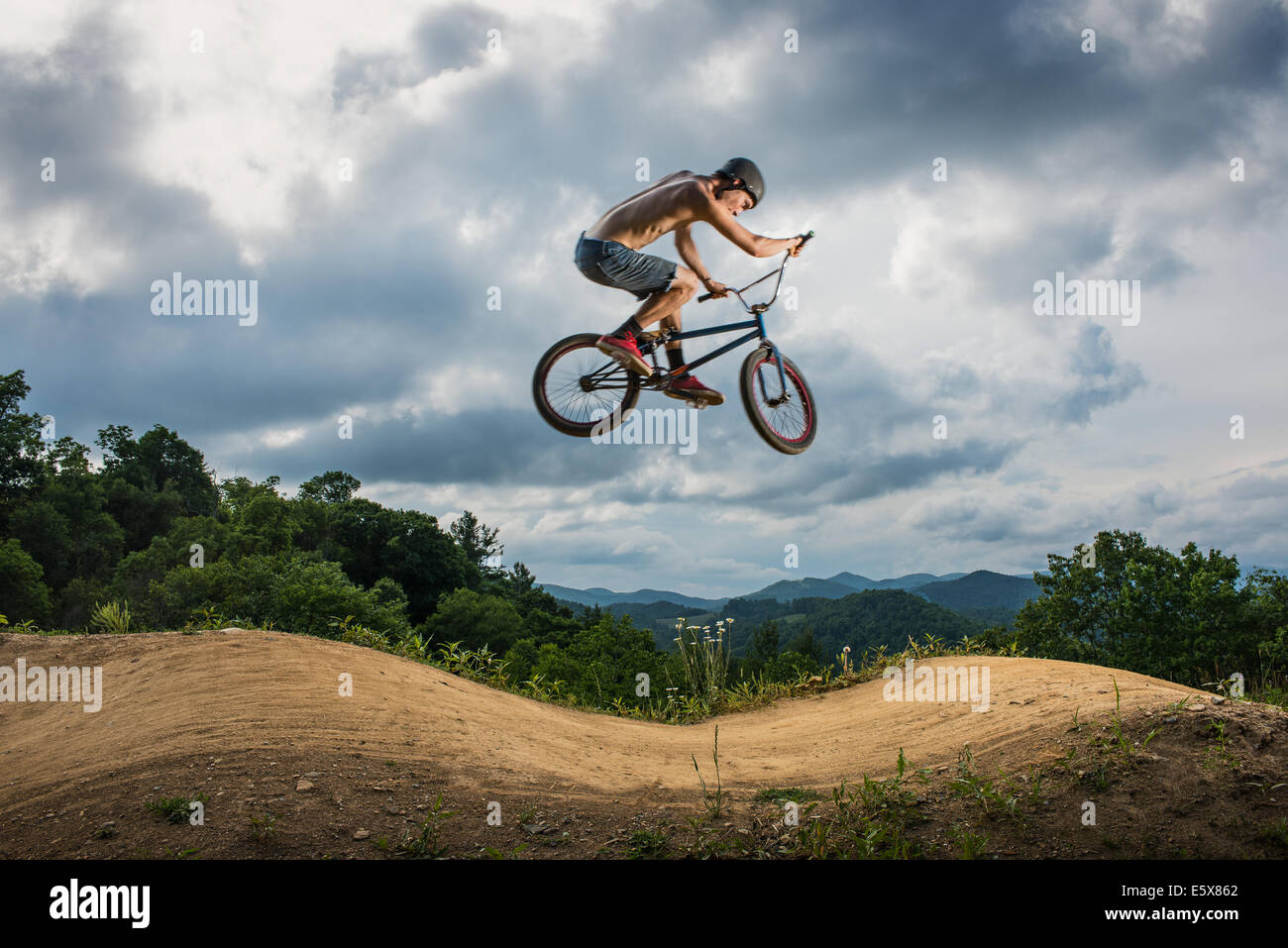 Giovane uomo facendo BMX trick su rurale pompa via Foto Stock