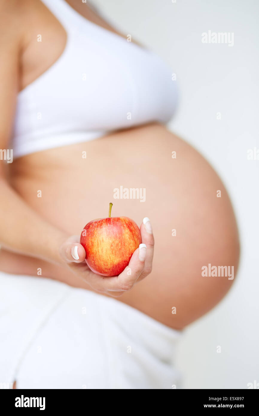 Donna incinta tenendo un Apple Foto Stock