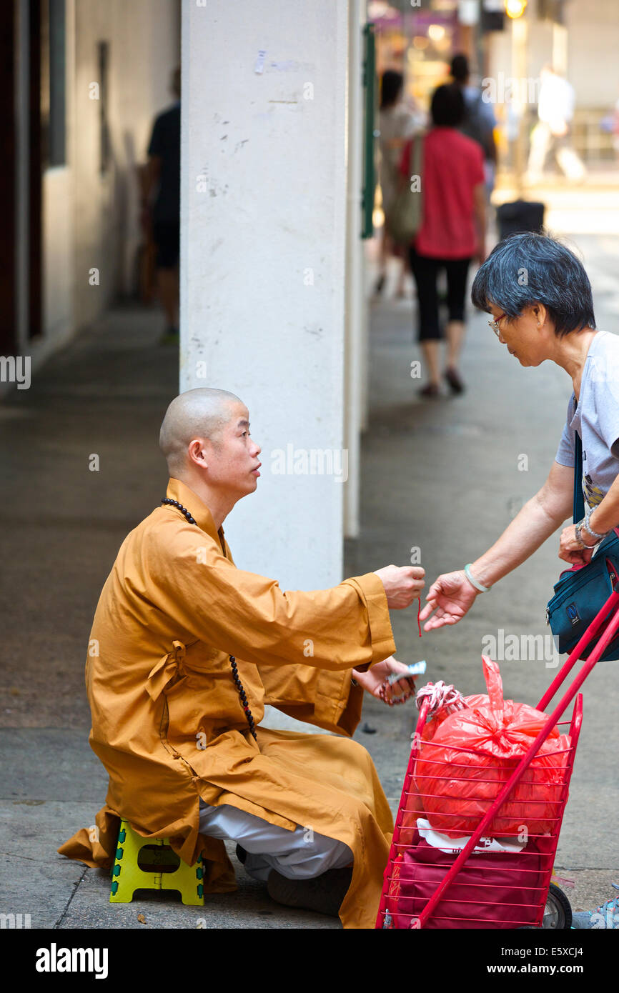 Donna cinese e un giovane monaco buddista su Chun Yeung Street, Hong Kong. Foto Stock