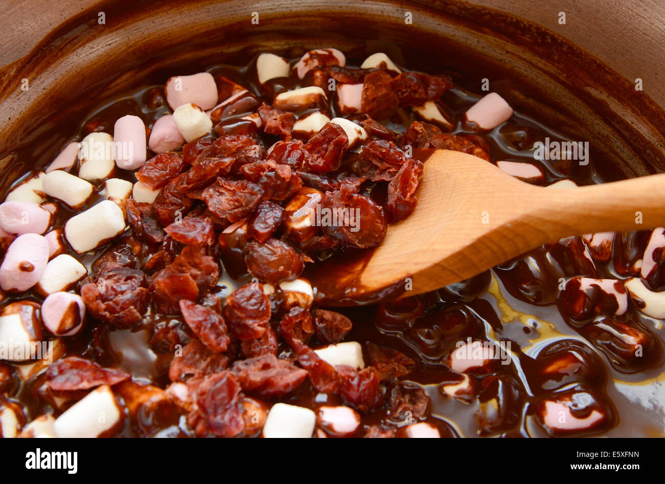 Aggiunta di mirtilli rossi secchi di marshmallows e cioccolato fuso per una strada rocciosa ricetta Foto Stock