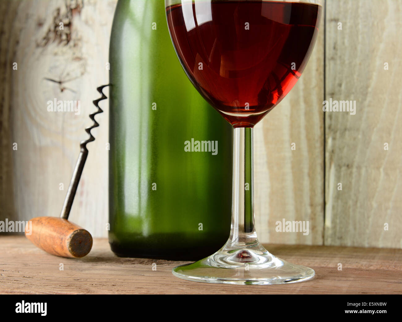Primo piano il vino ancora in vita con un vetro verde bottiglia e cavatappi contro un legno rustico sfondo. Formato orizzontale. Foto Stock