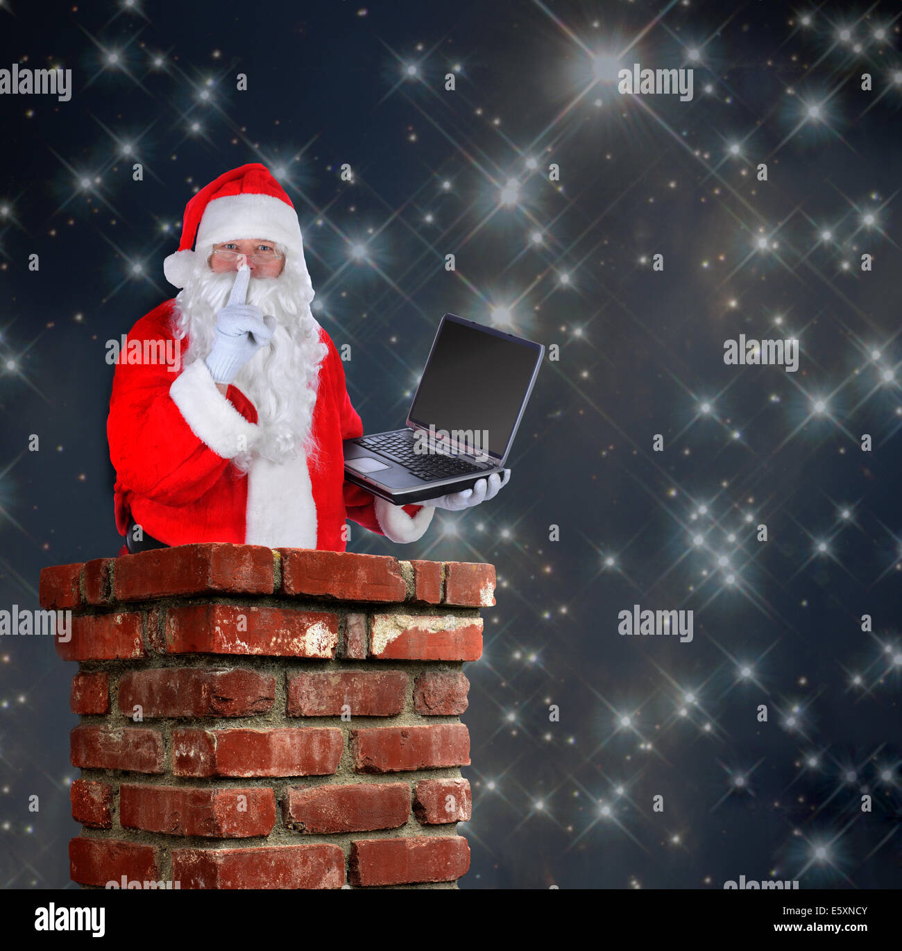 Santa Claus parzialmente all'interno di un camino con un computer portatile e di rendere il segno di shh con un dito per le sue labbra su una notte stellata backgro Foto Stock